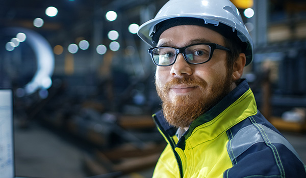 Kuvassa on tekniikan alan esihenkilö valkoisessa kypärässä.