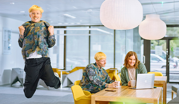 Kuvassa iloinen aikuisopiskelija hyppää ilmaan.